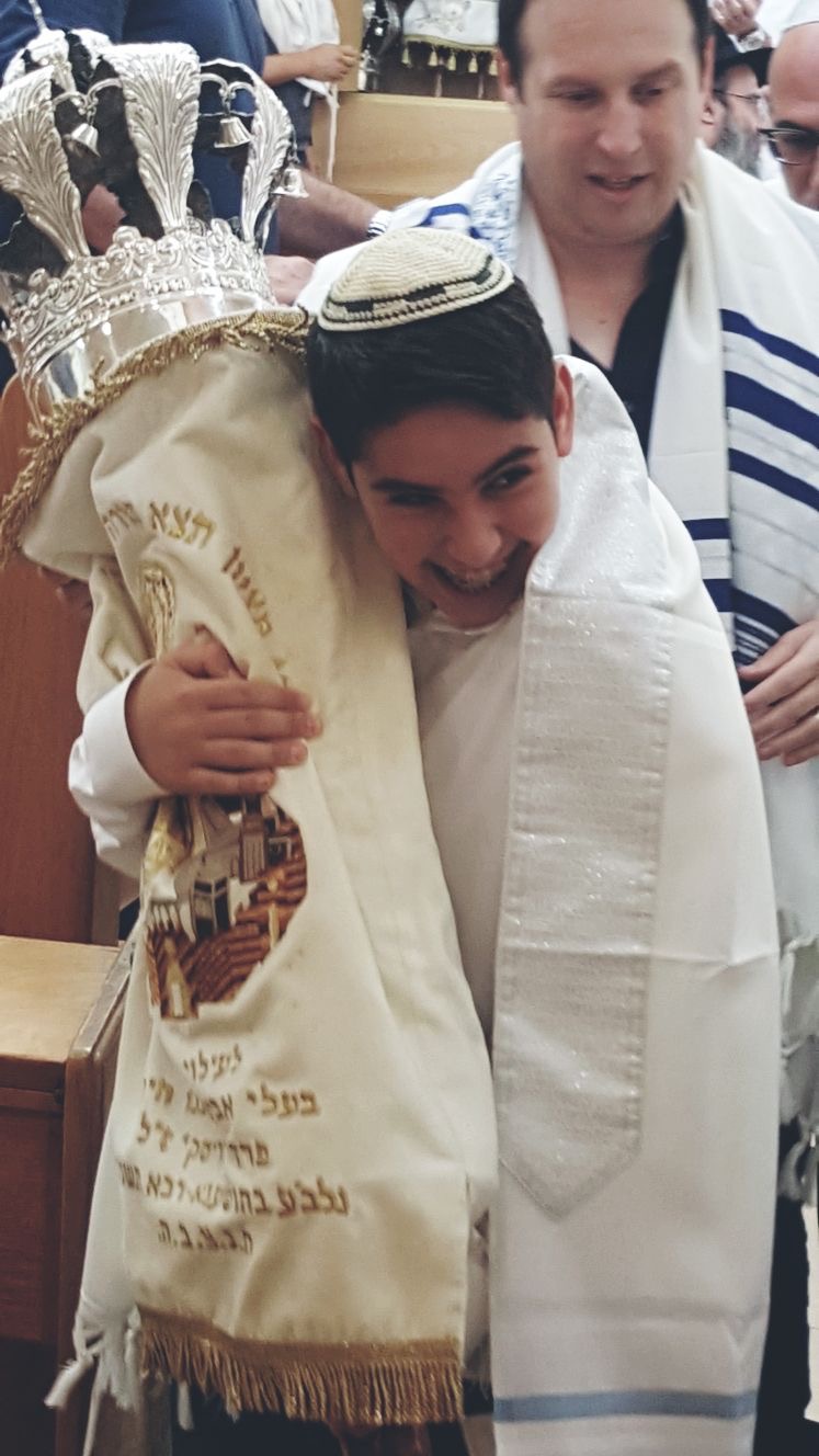 חתן בר המצווה מחבק את ספר התורה