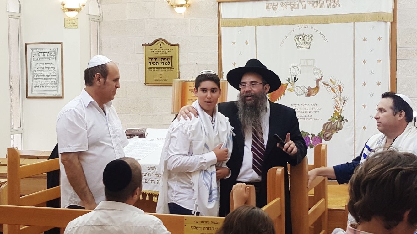המשפחה והרב סביב חתן בר המצווה בבית הכנסת